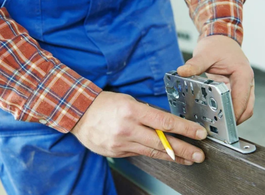 Мастер измеряет толщину двери под замок