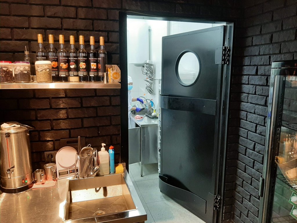 Черная маятниковая дверь кухни заведения общественного питания